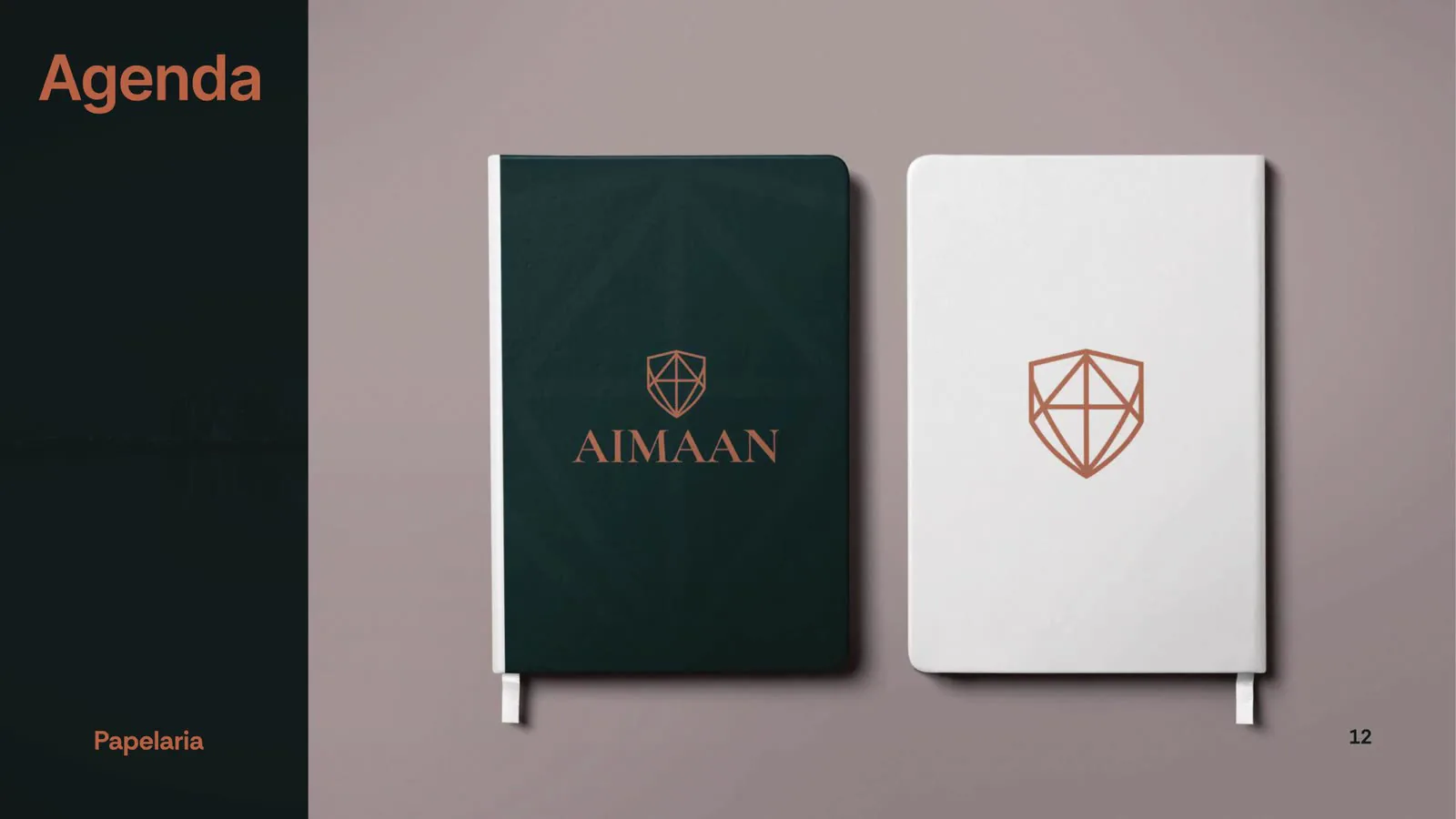 Agenda verde-escura e caderno branco com o símbolo em cobre na capa.