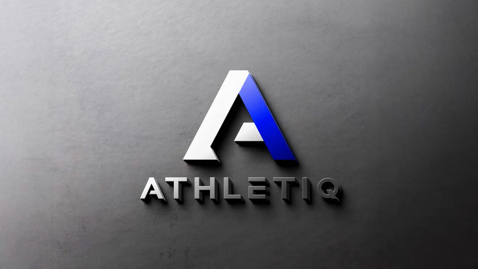 Logotipo em relevo sobre parede de concreto cinza, com luz rasante.