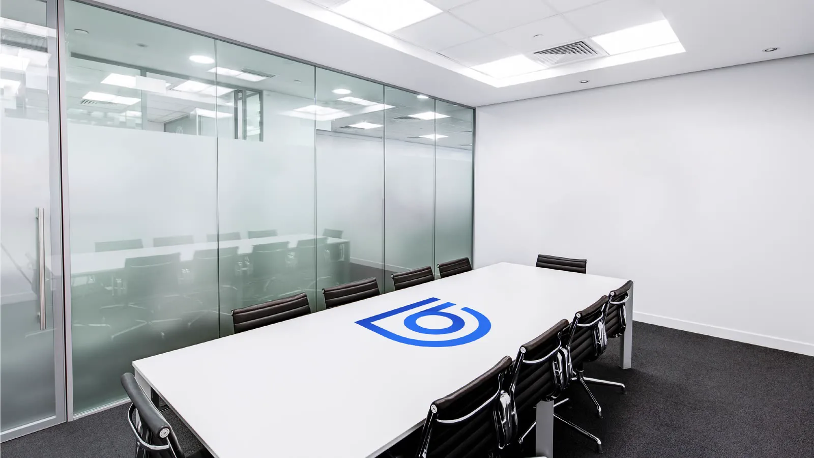 Sala de reunião envidraçada com o símbolo aplicado na mesa e no vidro.