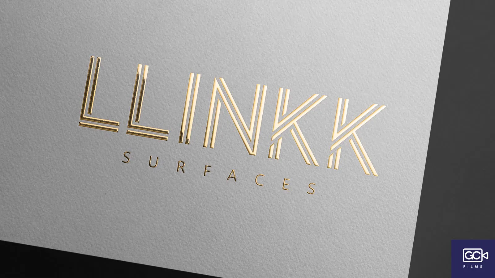 Logotipo em relevo dourado sobre papel branco de textura grossa.